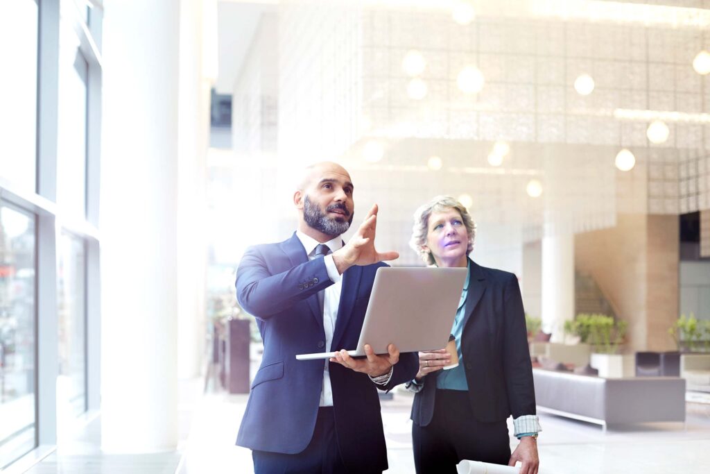 A man and a woman looking at something together while the man is holding a laptop.
