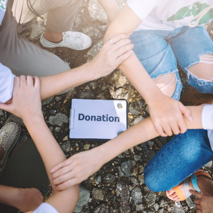 Fyra händer sammanfogade över en donationsskylt