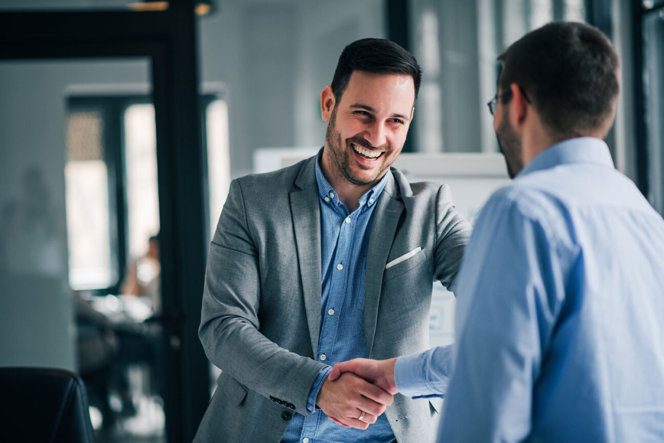 A man in a suit shaking a hand of another man.