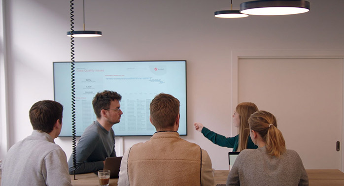 Devoteam Data team: a group of people watching a woman presenting something on a screen
