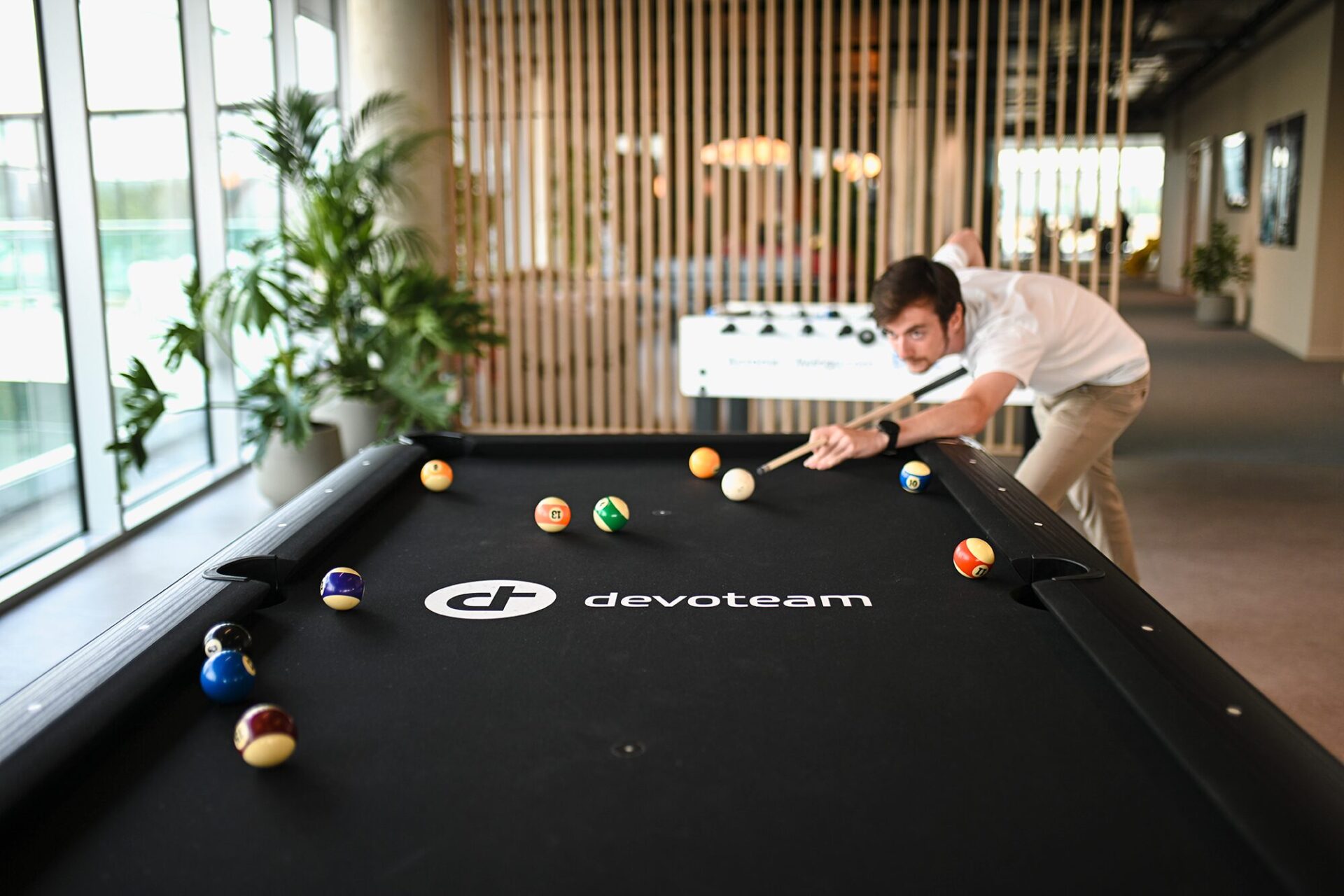 Devoteam Multi Cloud team: a man playing pool with a Devoteam logo