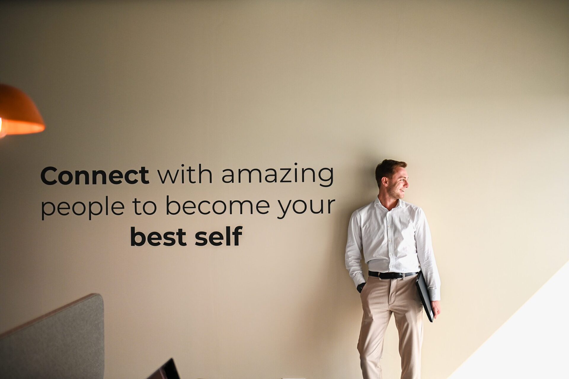 Devoteam Multi Cloud team: A man standing in front of the wall with a quote "Connect with amazing people to become your best self"