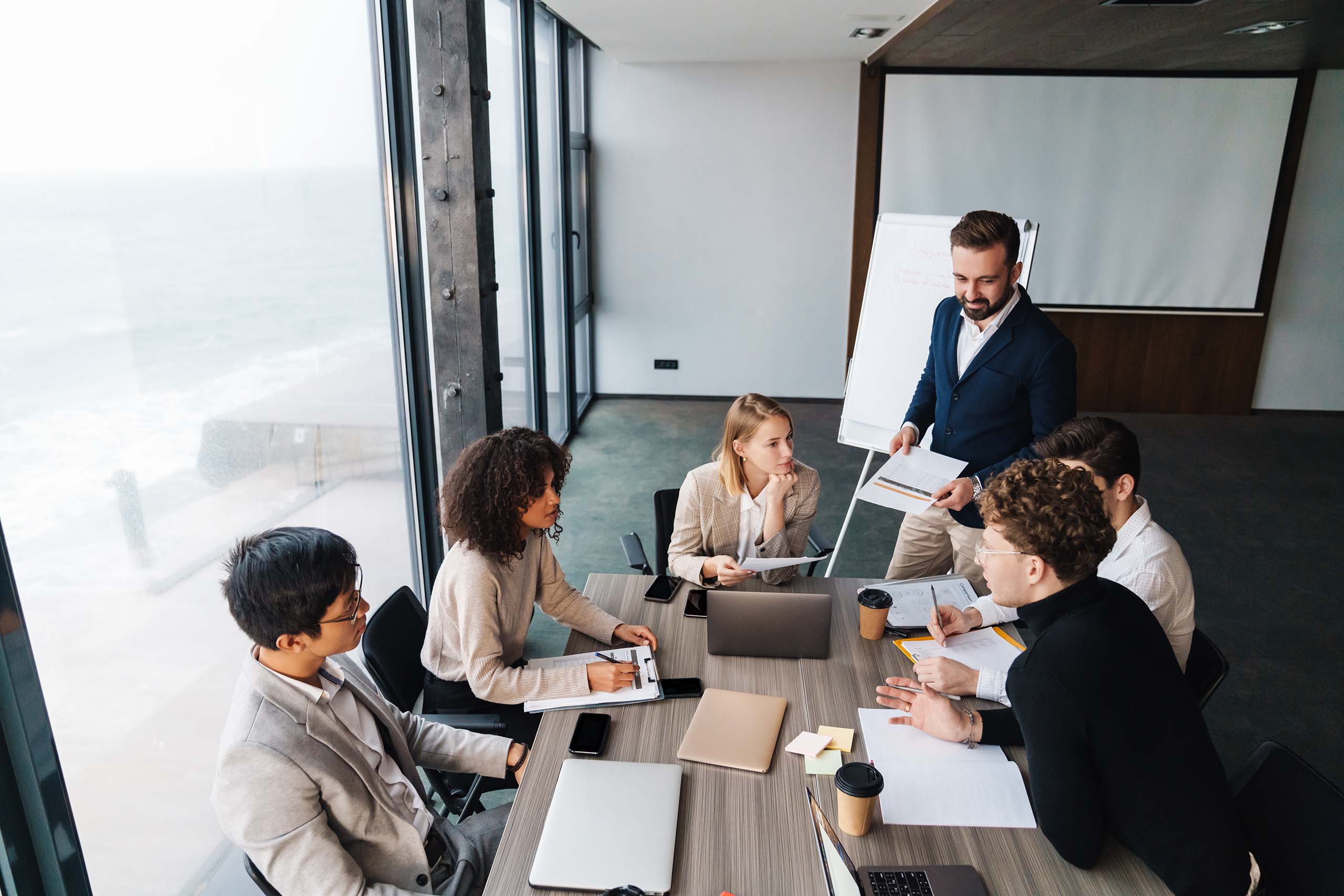 header image for devoteam corporate social responsibility people's page featuring diverse employees sitting around a desk