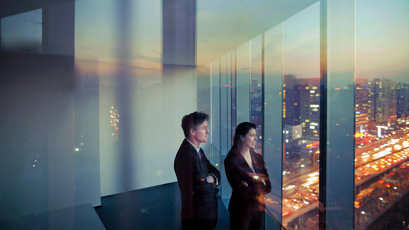 Image for Strategy: A man and a woman standing in front of a big window overseeing a city