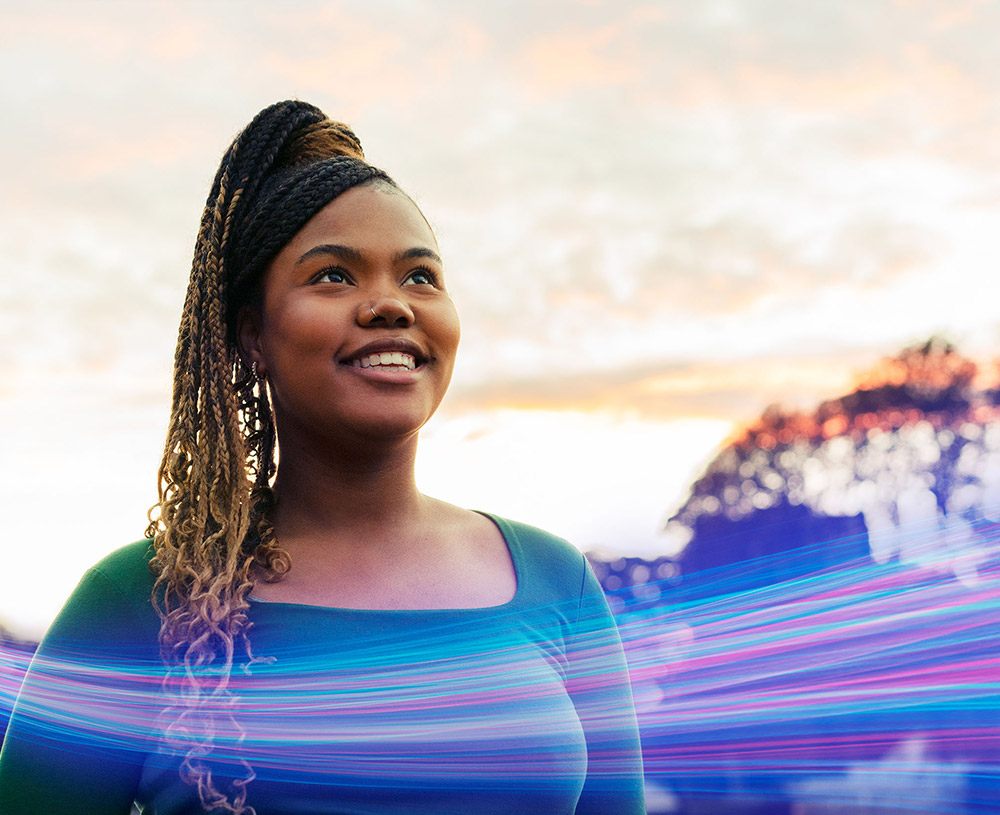 Light up your AI journey with AI Services image: a woman looking to the horizon with a strong of blue and purple light surrounding her